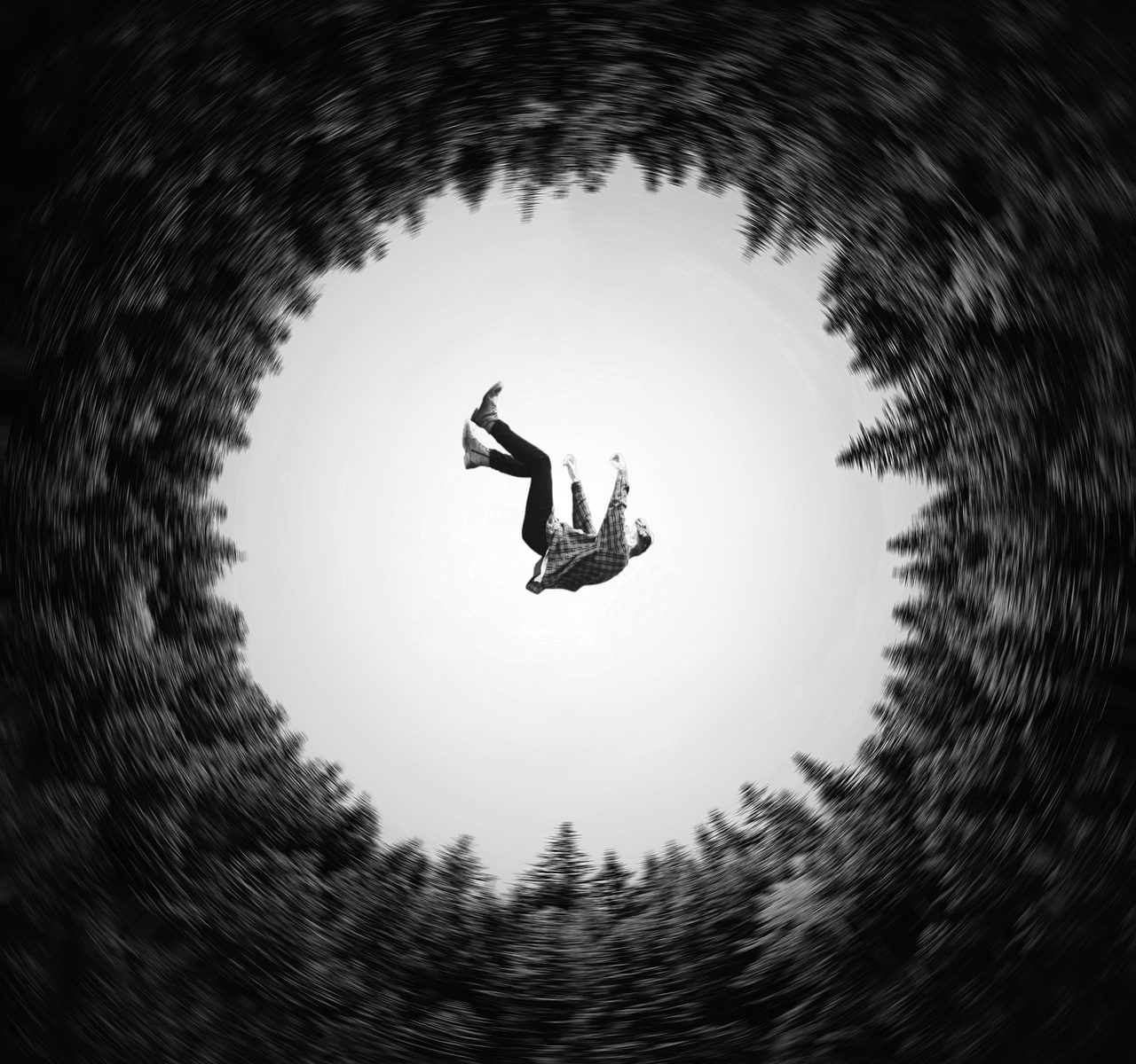 Looking up at a man falling into a circle of trees.